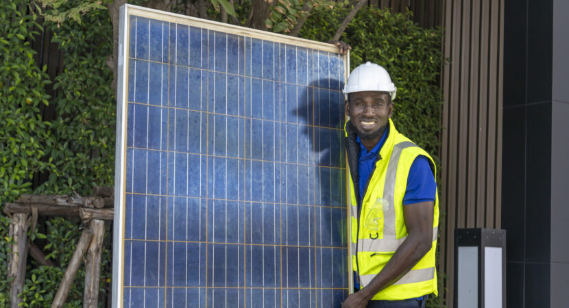 African American worker working on installing solar panel on the rooftop of the house for renewable energy and environmental friendly